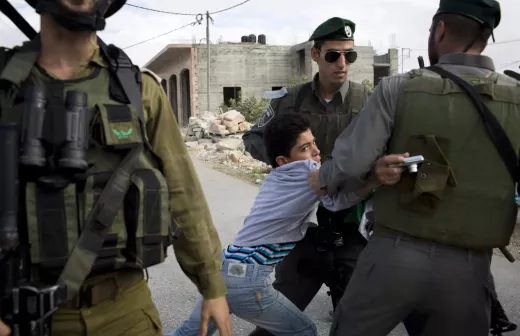 Israëlische bezettingssoldaten houden een terrorist met zijn wapen aan. Foto: palestinecampaign.org