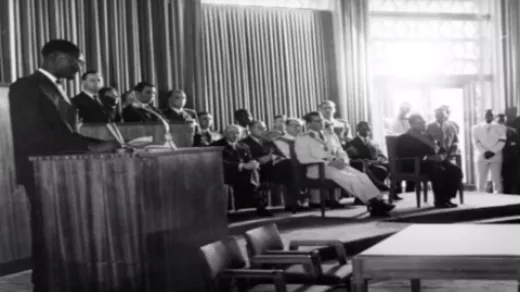 Eerste minister Lumumba (l) neemt onaangekondigd het woord op de plechtige zitting voor de verklaring van de onafhankelijkheid. Koning Boudewijn (in wit uniform) kijkt verontwaardigd toe. Foto: screenshot YouTube