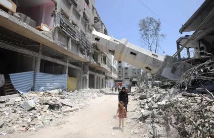 Een Palestijnse moeder en dochter stappen door wat ooit een winkelstraat en een minaret was in Gaza. UN Photo