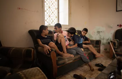 V.l.n.r.: Amro, 10, Ehab 12, Mohammad 6, Majed 5 zitten in hun overgrootvaders woonkamer. Een van de familiehuizen is vorig jaar afgebroken, het andere huis staat onder bedreiging om afgebroken te worden. Foto: Adeline Guerra/Oxfam 2020