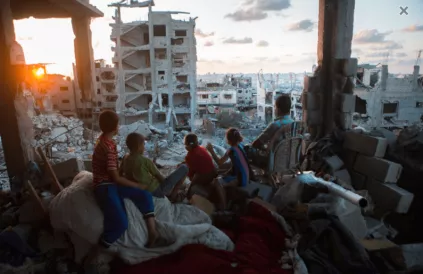 Een Palestijns gezin kijkt vanuit de ruïnes van hun huis naar de opkomende zon in de wijk at-Tuffah in Gaza-stad, kort na de bombardementen door het Israëlisch leger tijdens Operation Protective Edge in 2014. Foto: Anne Paq/activestills.org 