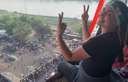 Boven het Turks restaurant aan Tahrirsquare in Bagdad kijkt deze betoogster goedkeurend toe. Aan de overzijde van de Tigris bevindt zich de Green Zone met de VS-ambassade en de ministeries. Foto: Ali Dab Dab