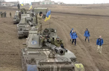 Tanks in Oost-Oekraïne. Ernaast in blauwe vest, monitoren van de OVSE. Foto: Wikimedia Commons