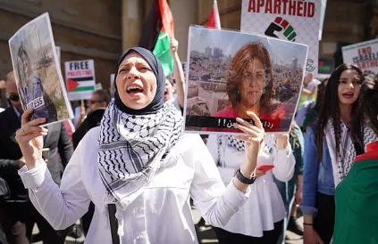Bij een protest in Londen houdt een betoger een portret van Shireen Abu Akleh, de auteur van dit artikel vast