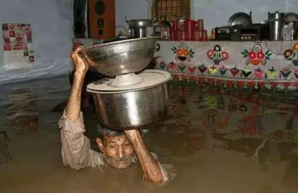 Een Pakistaan poogt wat huishoudgerief te redden. Foto: Pakistan Red Crescent
