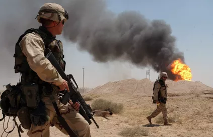 VS-soldaten bewaken een brandende oliebron in Rumailah, Irak. Foto: US Navy/Public Domain