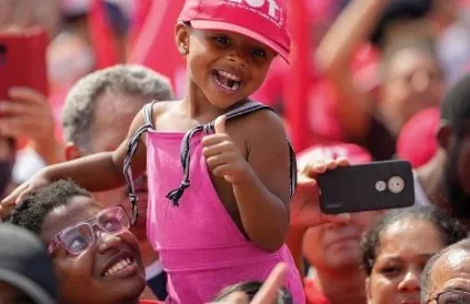 Een aanhanger van de Braziliaanse president Lula da Silva of the Workers Party steekt een meisje in de lucht op de May Day-meeting in Sao Paulo, Brazilië. Foto: Morningstar