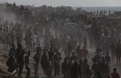 Palestijnen dragen voedselpakketten van de ‘Gaza Humanitarian Relief Foundation’ terwijl  Israël hen voortdurend beschiet. Foto: Omar Ashtawy/APAIImages