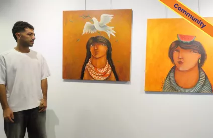 Hamada Elkept met twee van zijn schilderijen op de tentoonstelling. Foto: Martine Weemaels/Shine4 Palestine