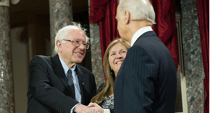 Bernie Sanders en Joe Biden schudden elkaar de hand.